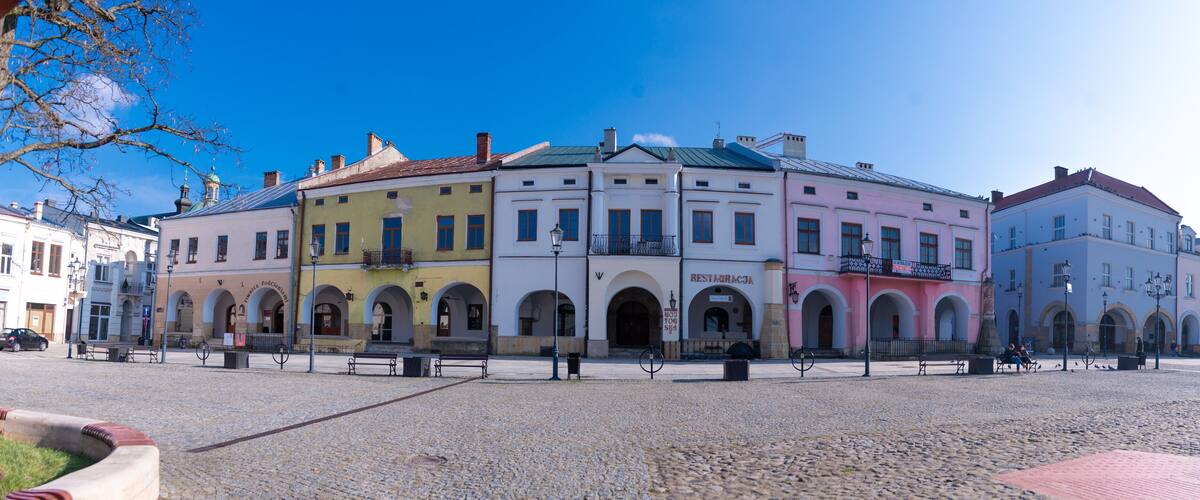 A cobblestone square with colorful buildings, benches, and a clear blue sky.