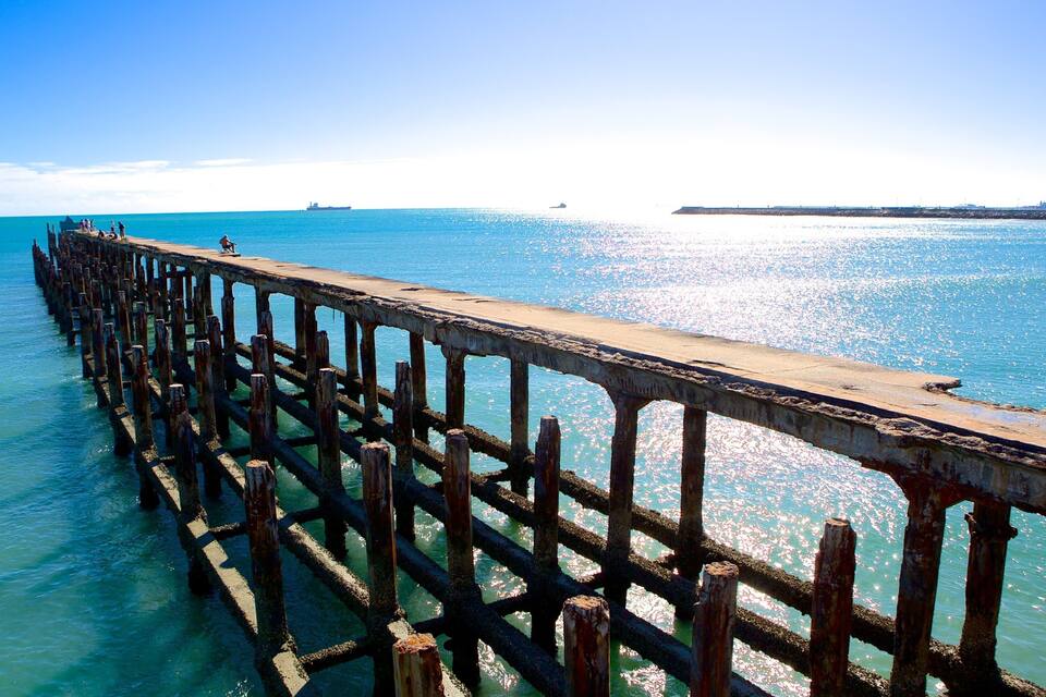 A long pier extending into a calm sea with clear skies.