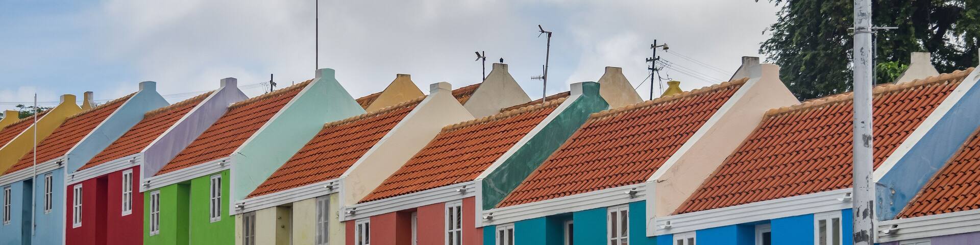 A row of colorful houses with red-tiled roofs and white trim.