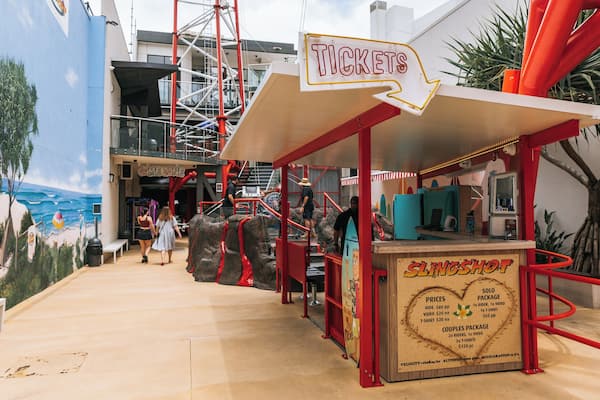 A ticket booth with a sign for 'TICKETS' and a 'SLINGSHOT' game area.