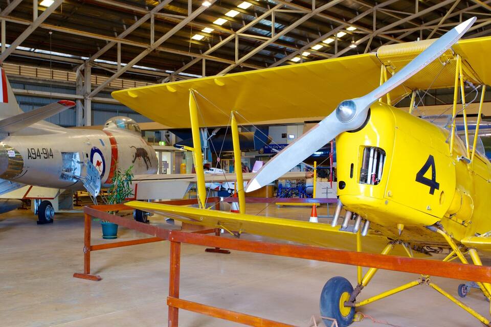 A yellow biplane with the number 4 on its nose, a white biplane with the number 76, and a French flag on the tail of the white biplane.