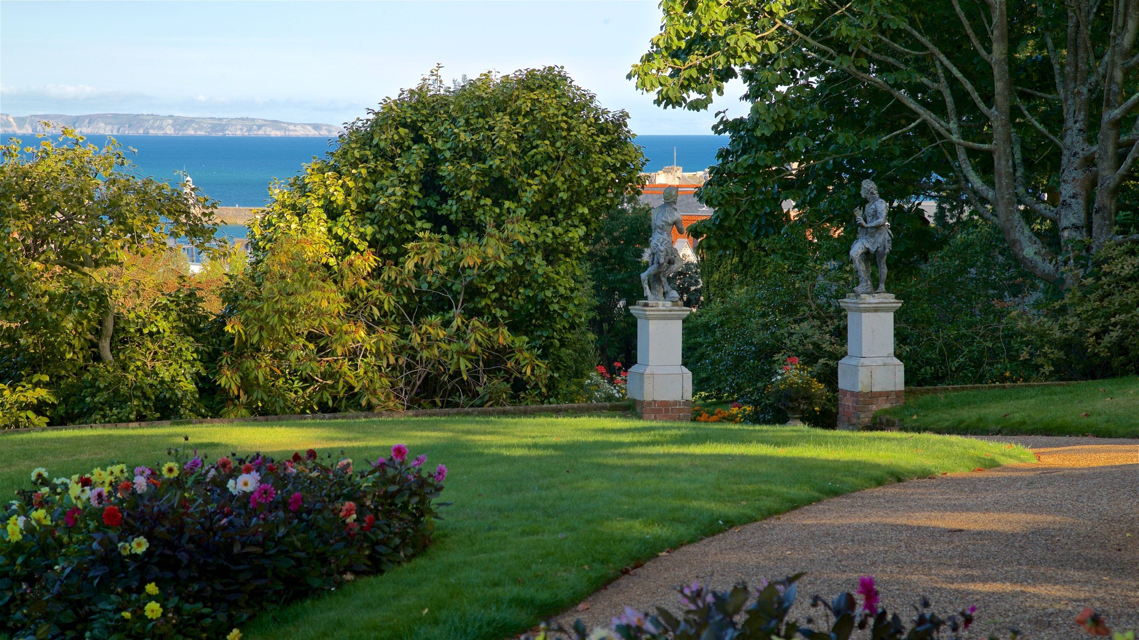 Un jardin agrémenté de statues, une pelouse et une vue sur la mer.