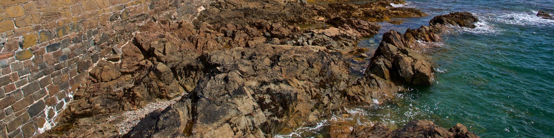 Castle Cornet which includes general coastal views and rocky coastline