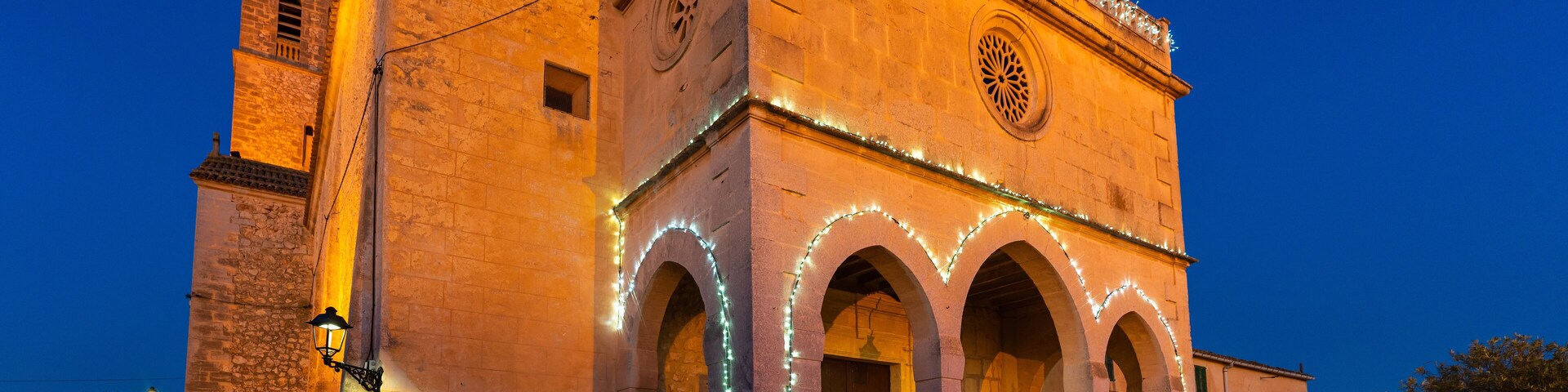 A historic building with illuminated arches and a clock tower at dusk.