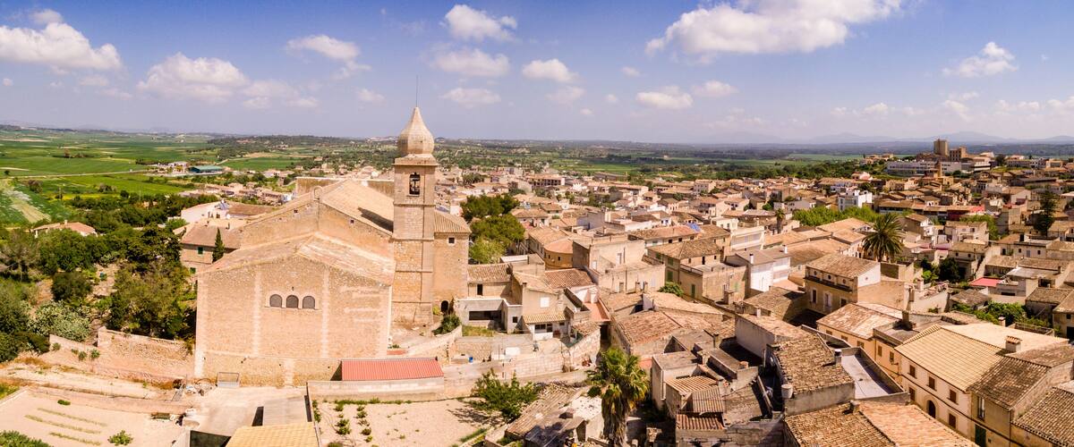 A historic town with a prominent church, terraced fields, and rolling hills in the background.