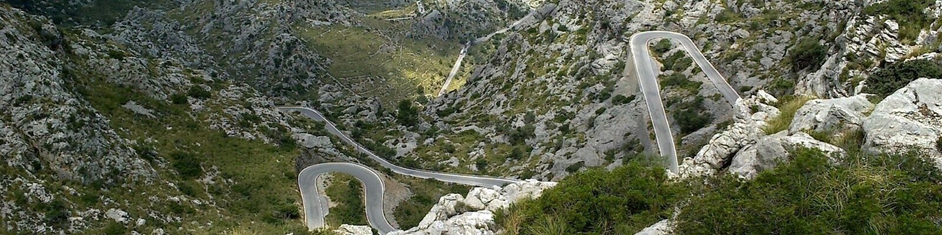 Una carretera sinuosa entre montañas, rodeada de terreno rocoso y vegetación escasa.