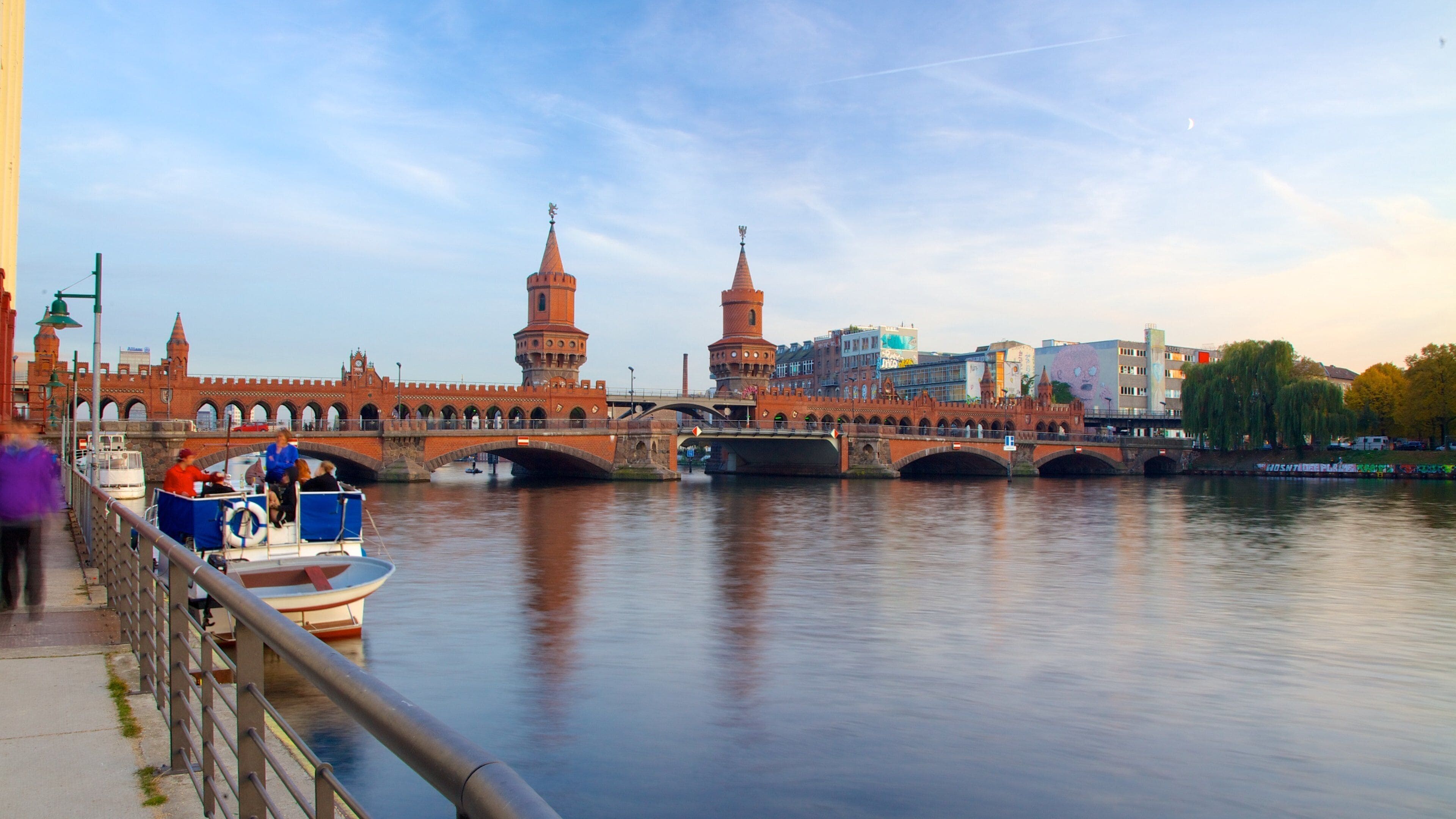 A historic bridge with two towers, a river, and a boat docked on the left.