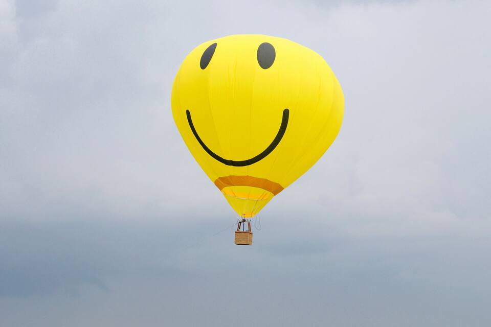 A yellow hot air balloon with a smiley face design.