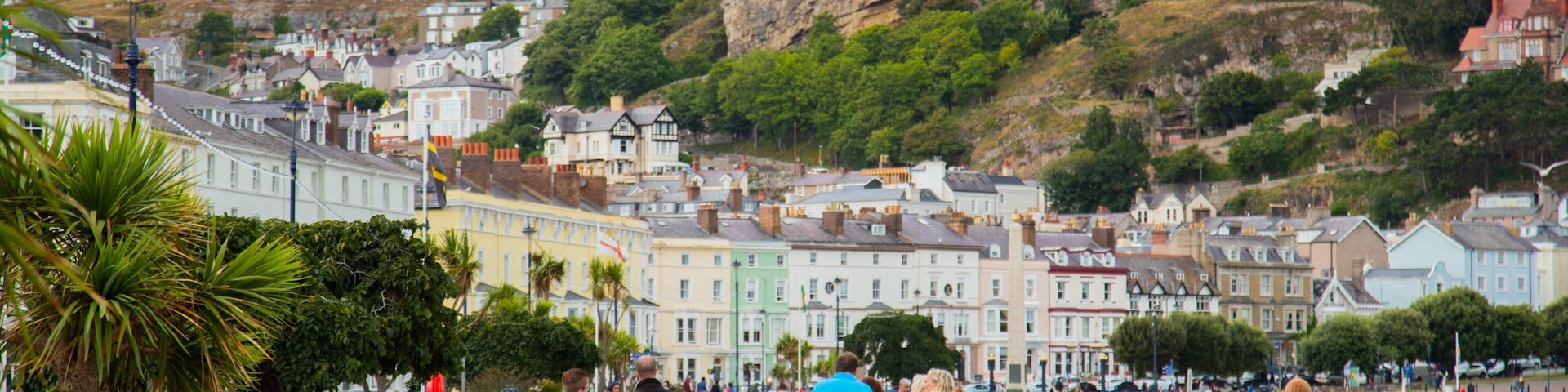 A coastal town with colorful buildings, a promenade, and a hillside in the background.