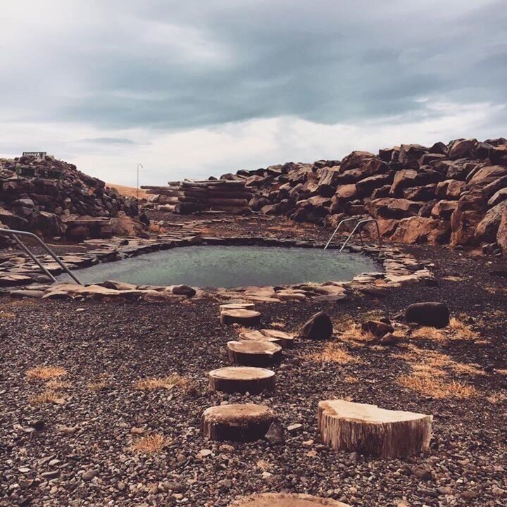 A natural hot spring surrounded by rocks and pebbles.