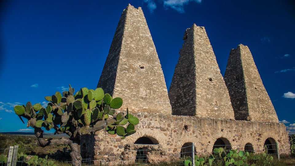 A stone structure with three tall towers and arched openings.