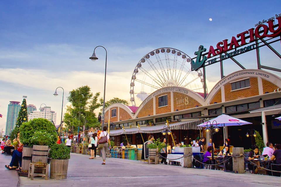A bustling street with a Ferris wheel, a sign for "ASIA TATTOO," and a city skyline in the background.