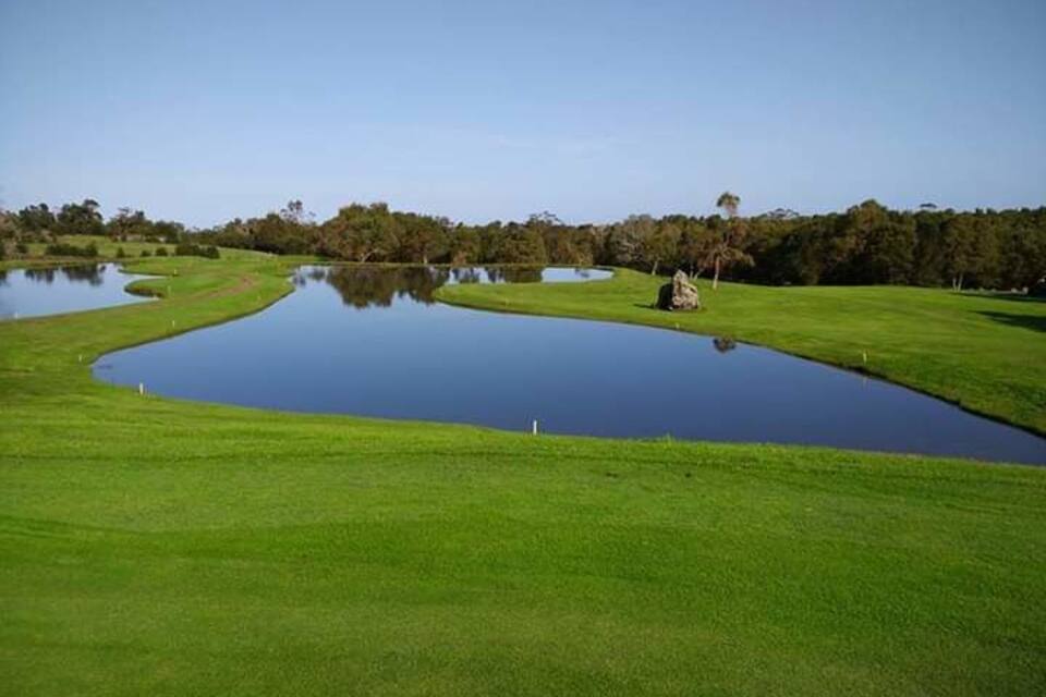 A golf course with multiple ponds and a large rock.