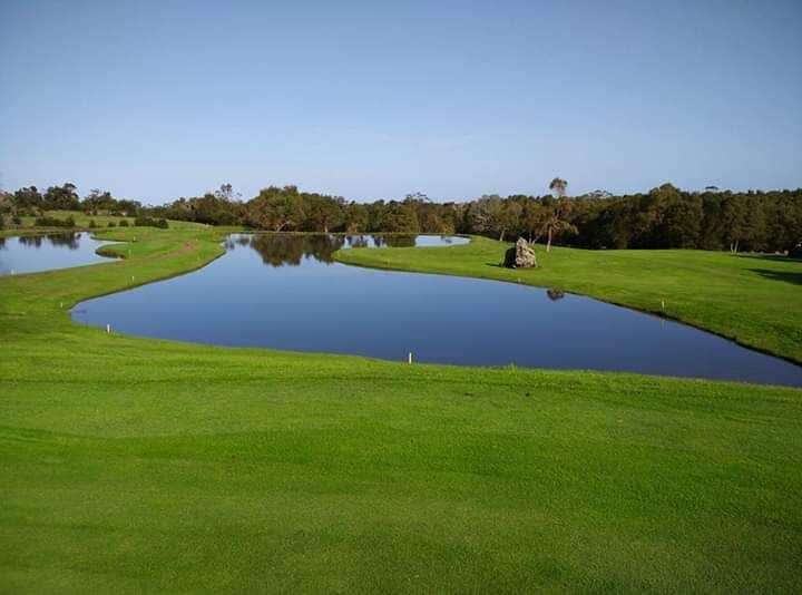 A golf course with multiple ponds and a large rock.