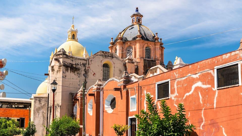 A historic church with a yellow dome and a red building with a blue dome.