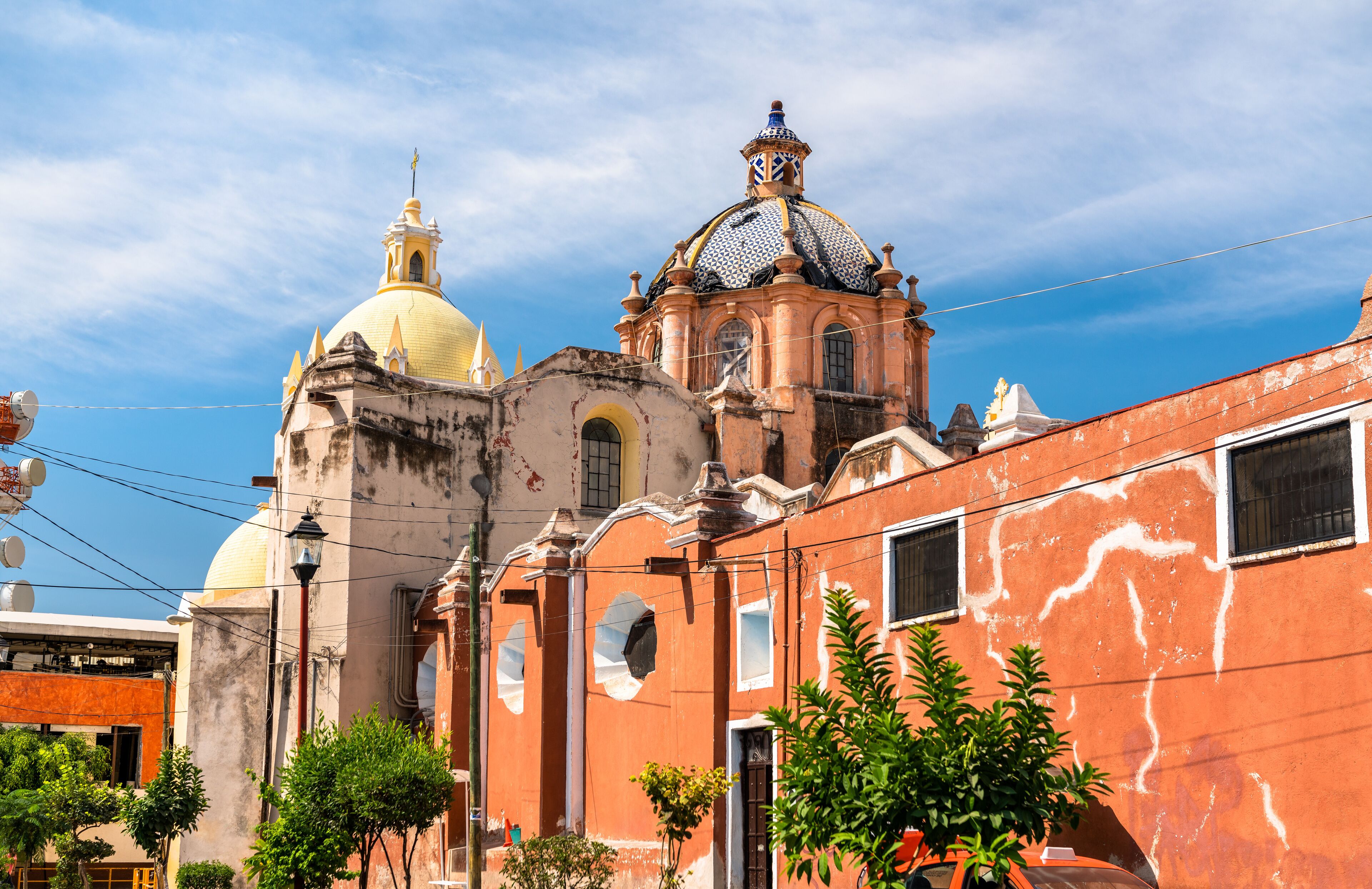 A historic church with a yellow dome and a red building with a blue dome.