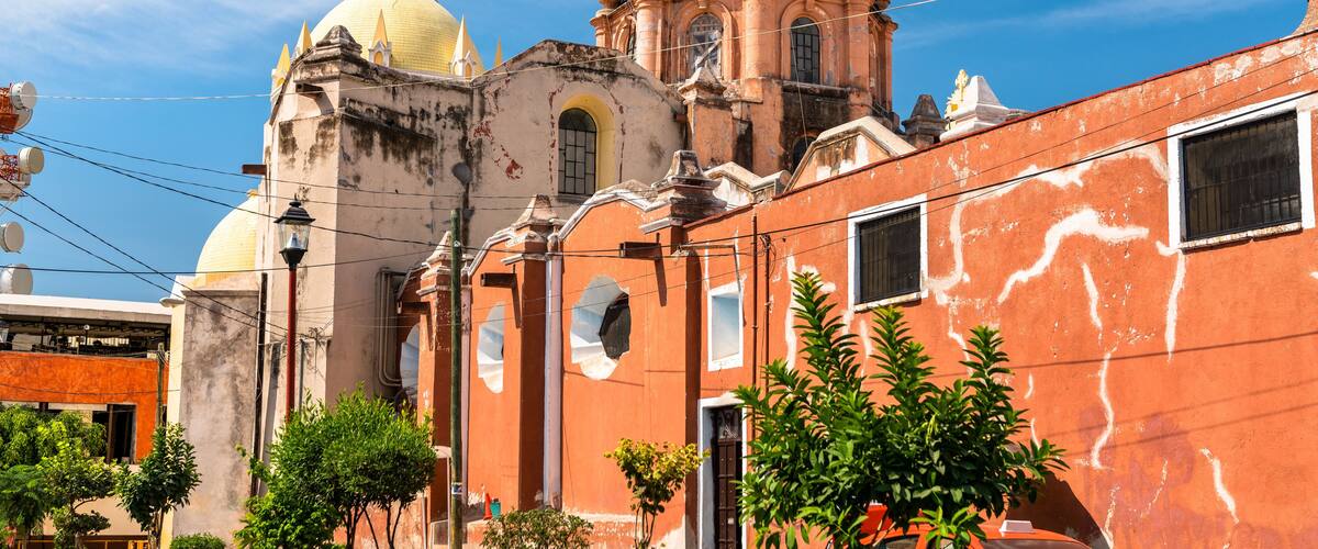 A historic church with a yellow dome and a red building with a blue dome.