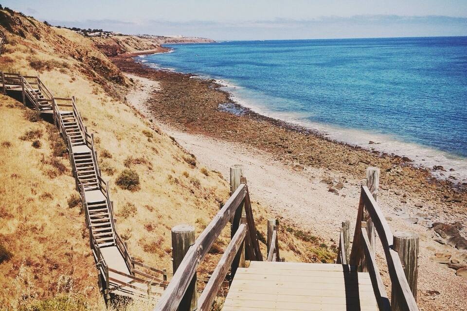 A wooden boardwalk leading to a beach with clear blue water.