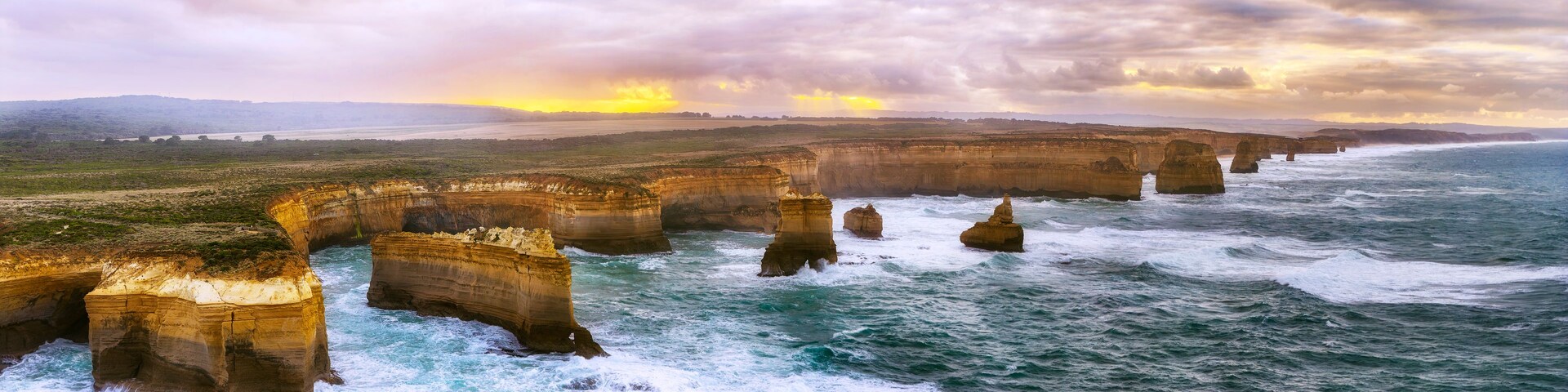 A coastal landscape with prominent rock formations and a sunset.