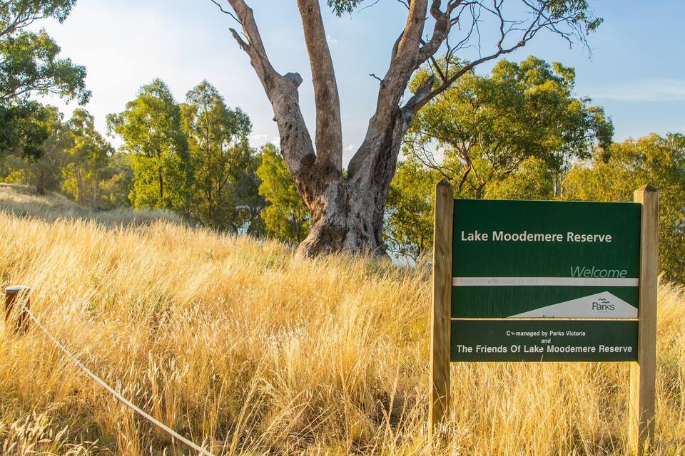 Señal para la Reserva del Lago Moomerere, con hierba alta y árboles al fondo.