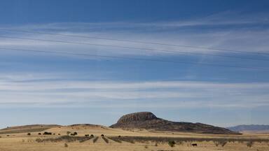 A flat landscape with a prominent hill and power lines in the distance.