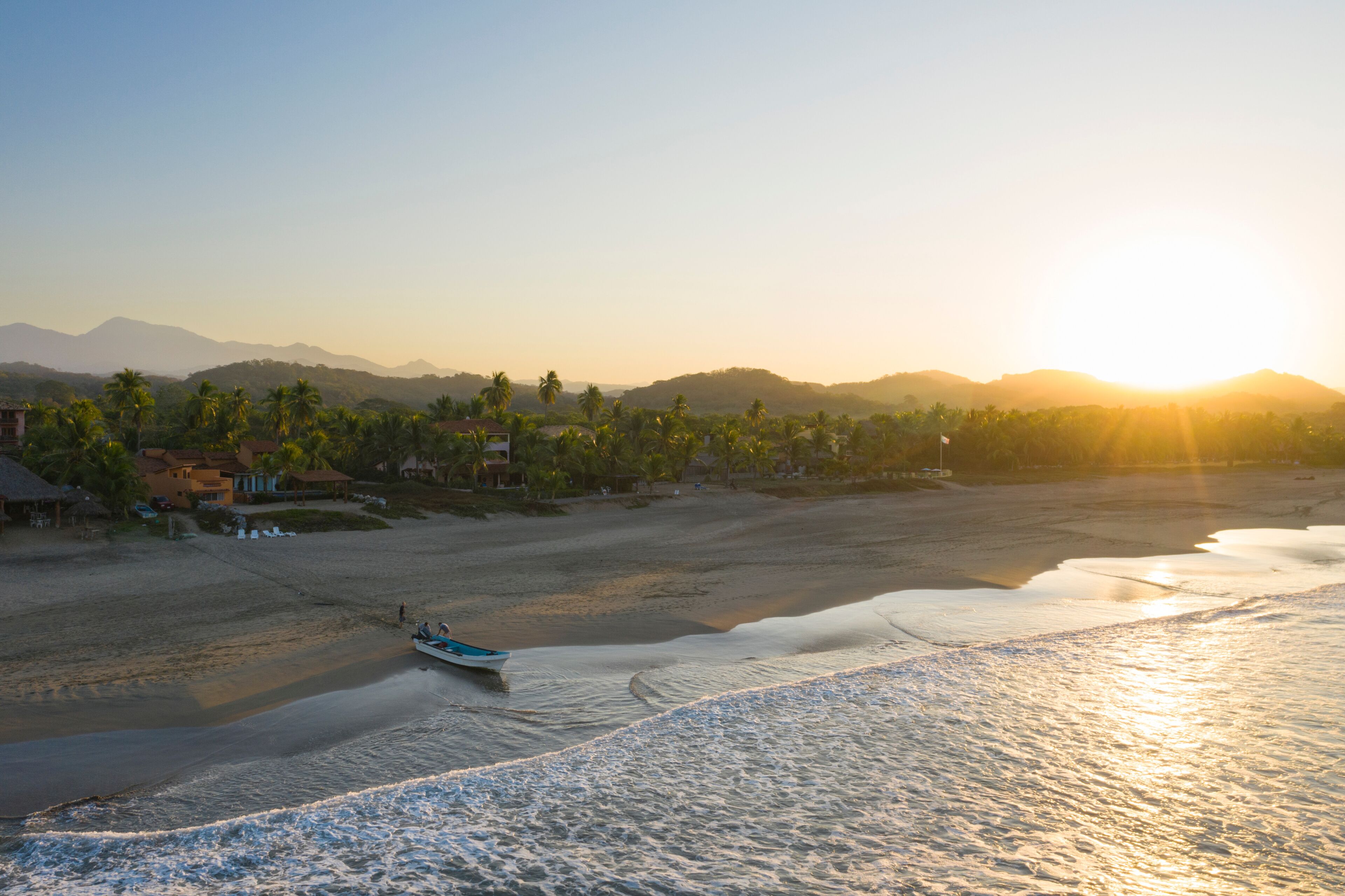 Aerial view of tranquil Playa Troncones with a fishing boat at sunrise, Guerrero, Mexico.