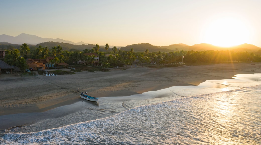 Aerial view of tranquil Playa Troncones with a fishing boat at sunrise, Guerrero, Mexico.