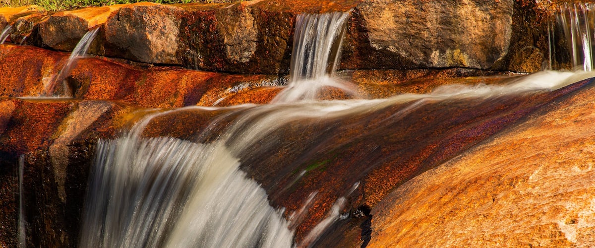A waterfall cascading over reddish-brown rocks.