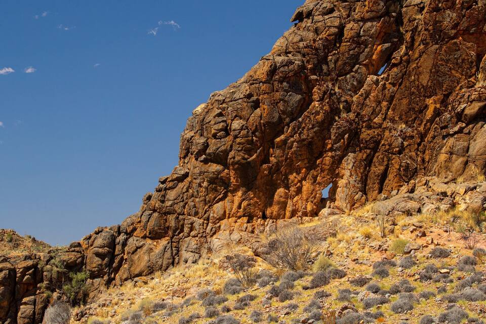 A rugged rock formation with sparse vegetation.