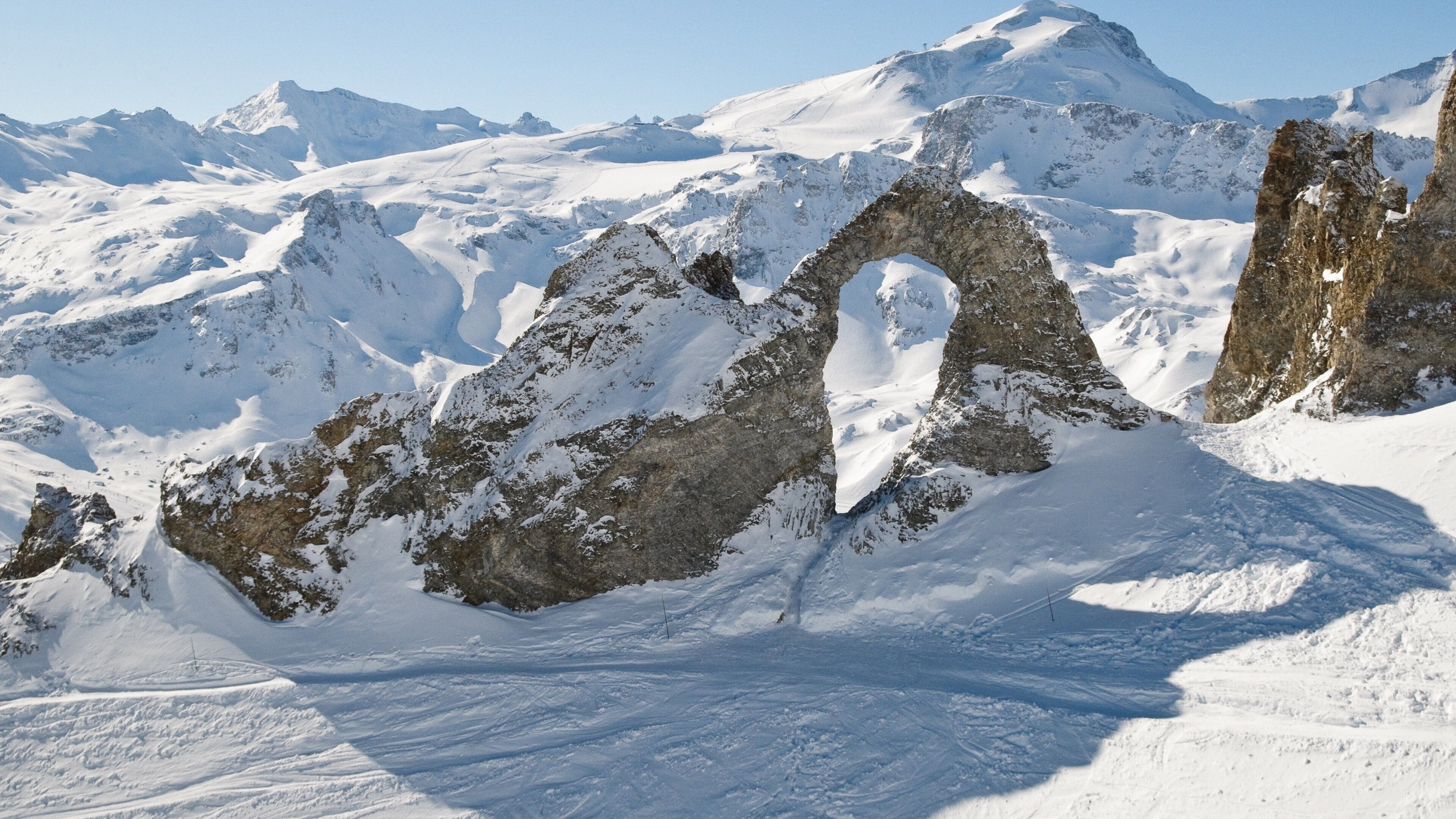 Una montaña nevada con un arco rocoso destacado.