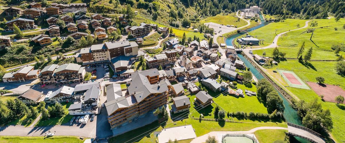 A mountainous village with traditional wooden houses, a river, and a bridge.