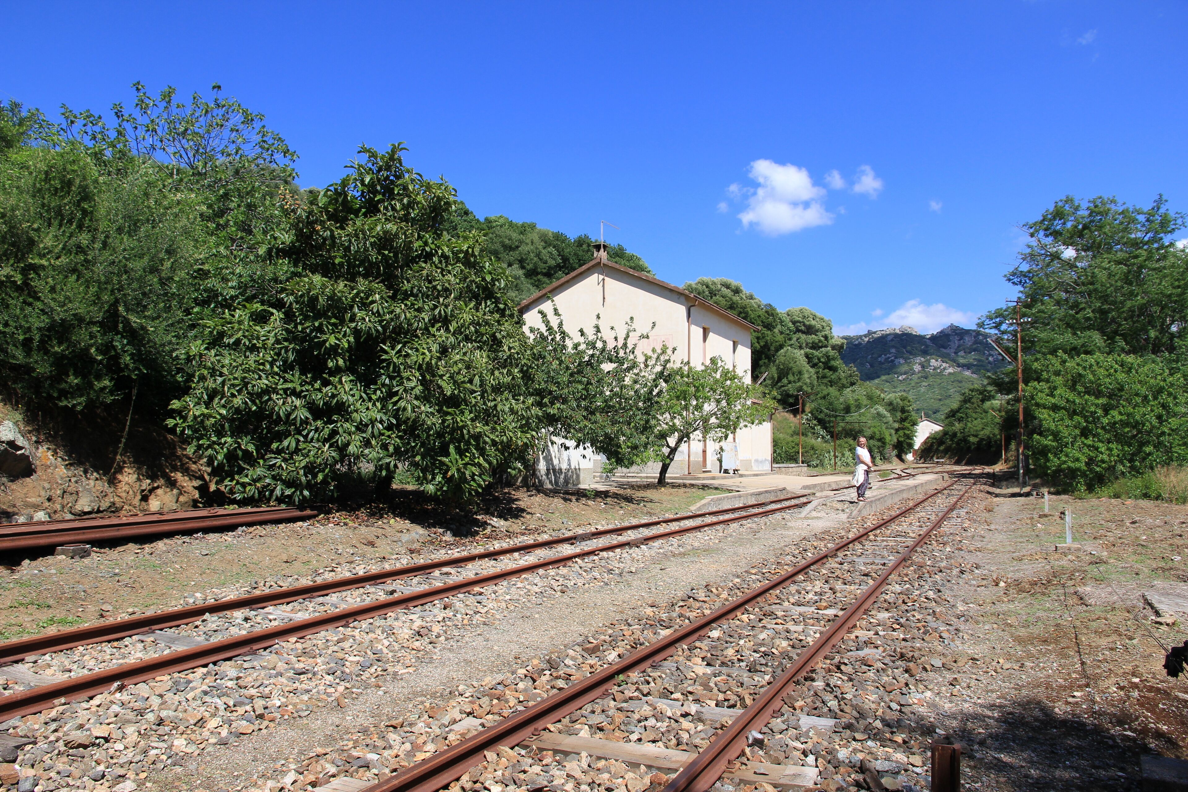 A railway track with a building and trees in the background.
