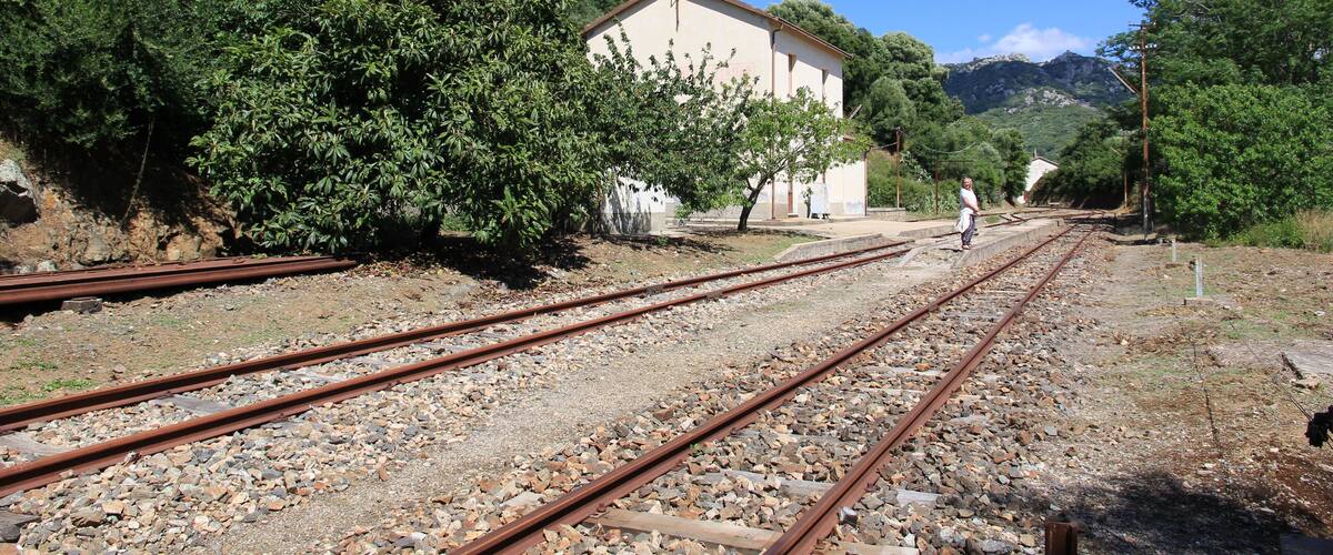 A railway track with a building and trees in the background.