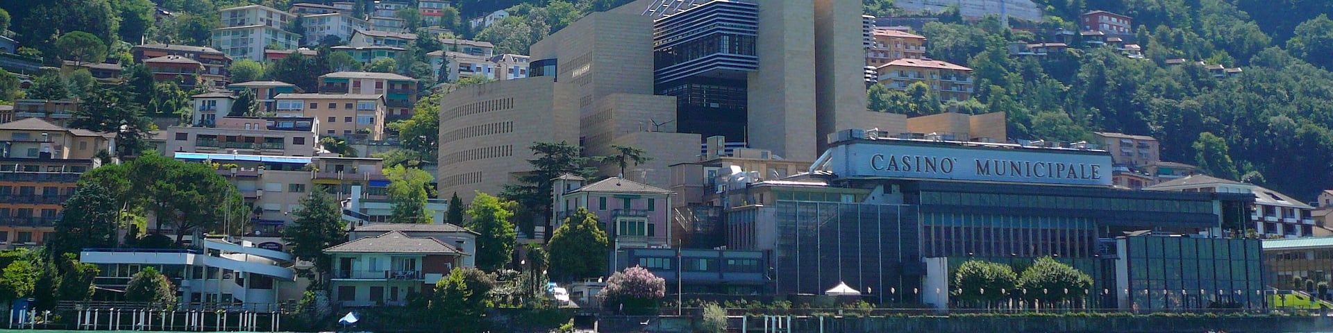 A coastal town with a casino named 'Casino Municipale' and lush green mountains in the background.
