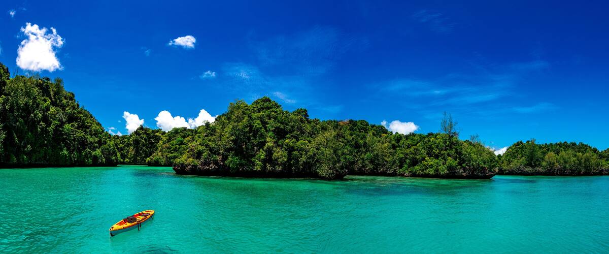 A turquoise sea with a small boat, surrounded by lush green islands.