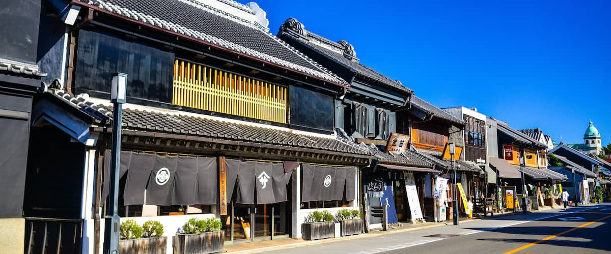 A street lined with traditional Japanese buildings with tiled roofs and storefronts.