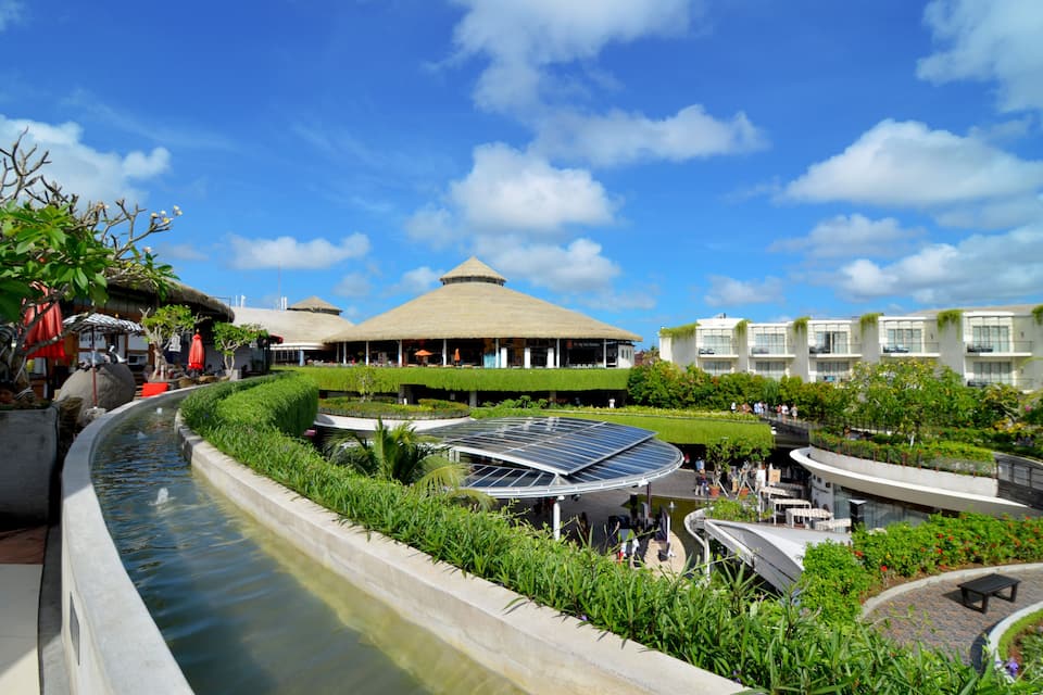 A resort with a water feature, a thatched-roof building, and a solar panel structure.