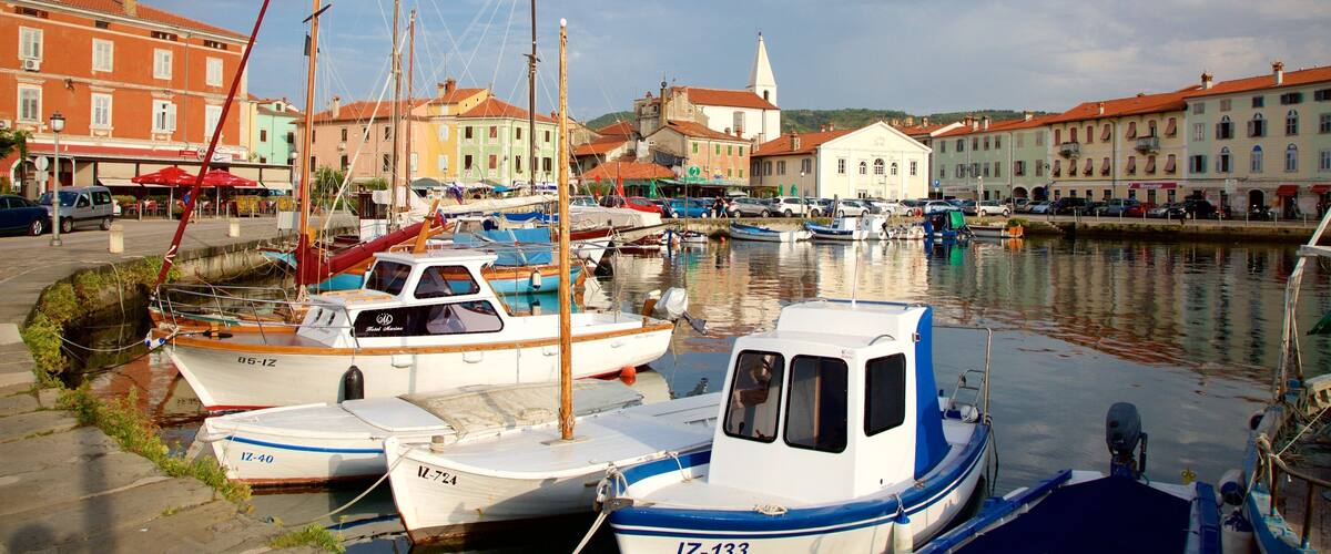 A marina with several boats docked, surrounded by colorful buildings and a church in the background.