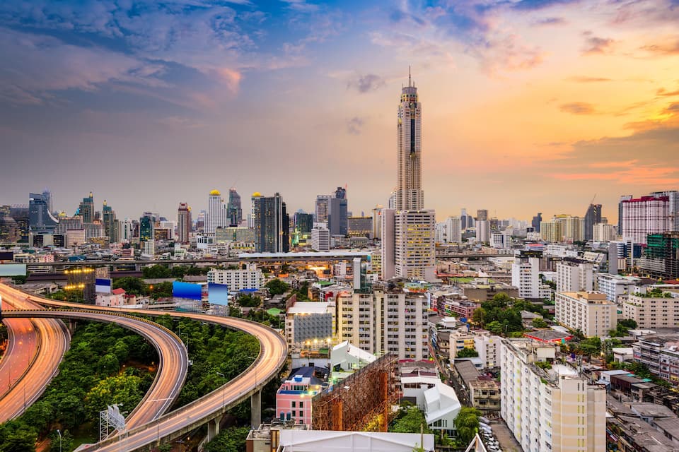 A cityscape with a prominent skyscraper, a curved highway, and dense urban buildings.