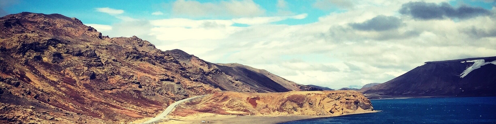 Un paisaje costero con montañas escarpadas, un camino sinuoso y un mar tranquilo.