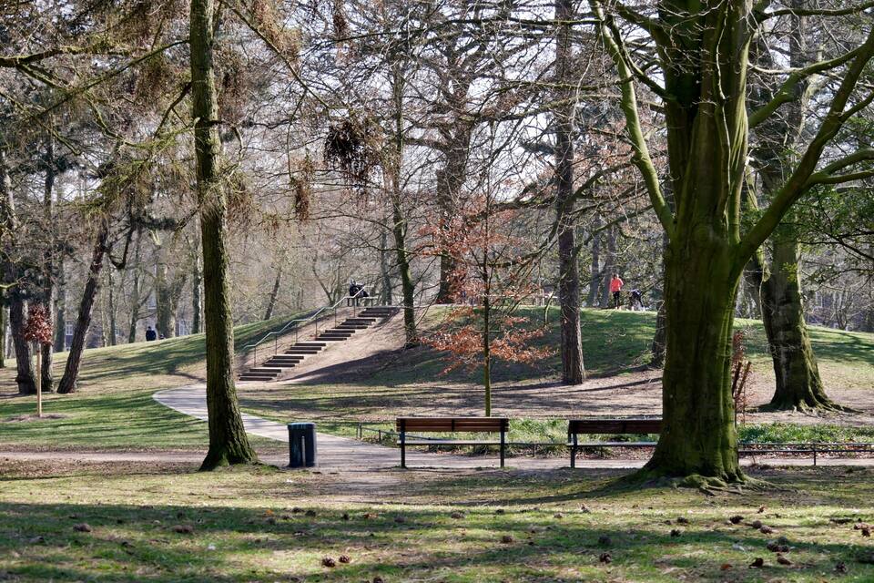 Un parc amb un camí sinuós, bancs i una escala que puja una collada.