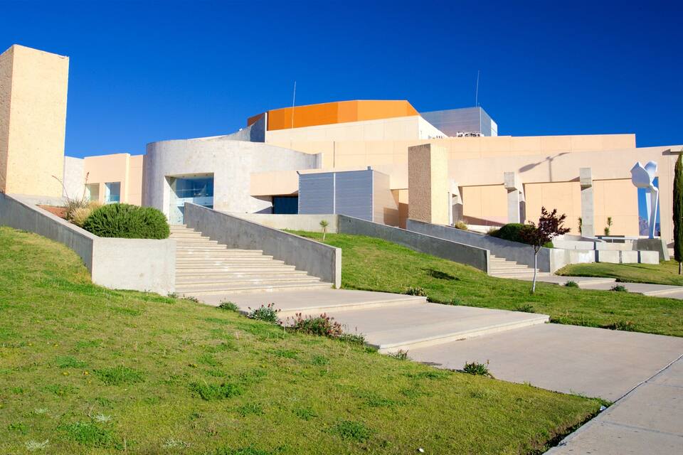 Un bâtiment moderne doté d’une architecture originale, caractérisé par un toit orange bien visible et une série de marches menant à l’entrée.