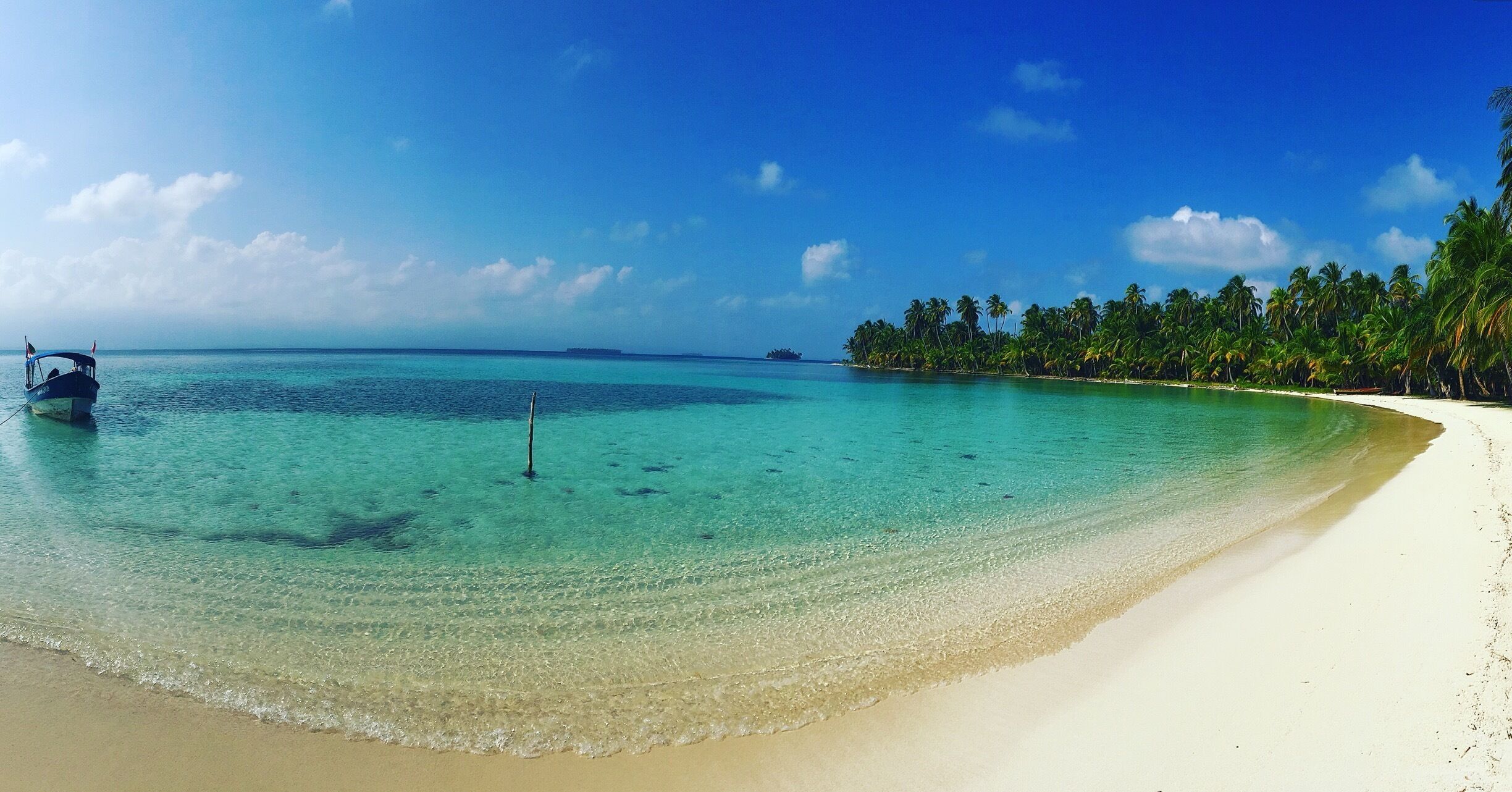 A beach with clear turquoise water, white sand, and palm trees.