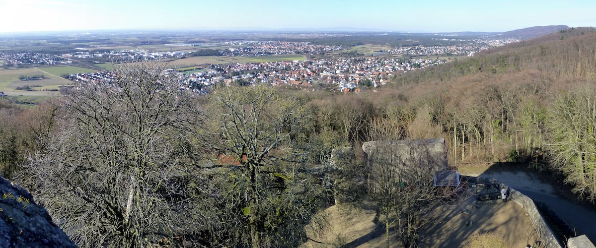 A panoramic view of a town nestled in a valley, surrounded by hills and sparse trees.