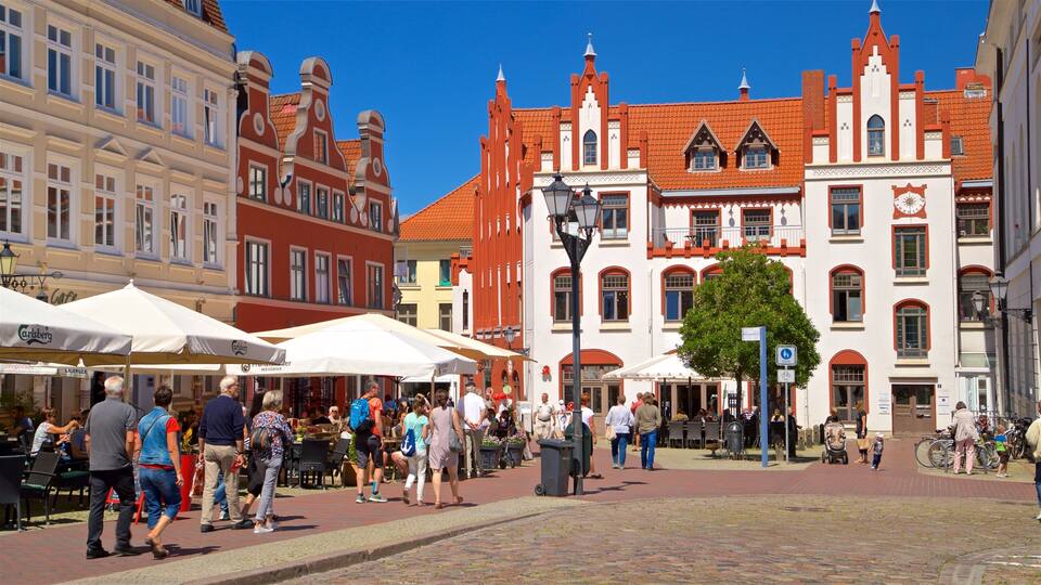 Une place animée au cœur de l’Europe, bordée de bâtiments historiques, de cafés en plein air et surplombée d’un ciel d’un bleu éclatant.