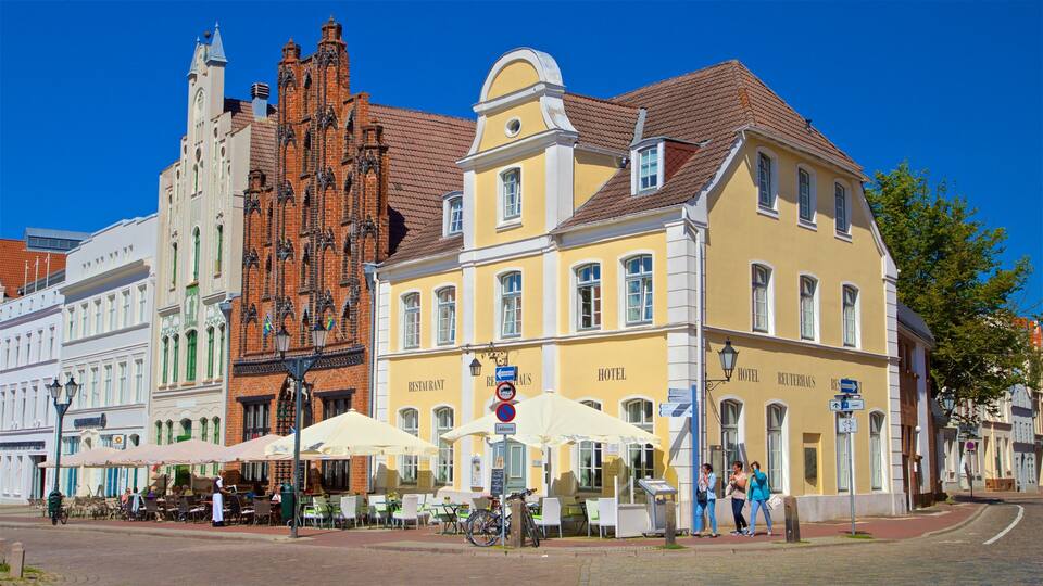 Un bâtiment historique à la façade en briques rouges et un bâtiment jaune sur lequel on peut voir une enseigne indiquant la présence d’un restaurant et d’un hôtel.