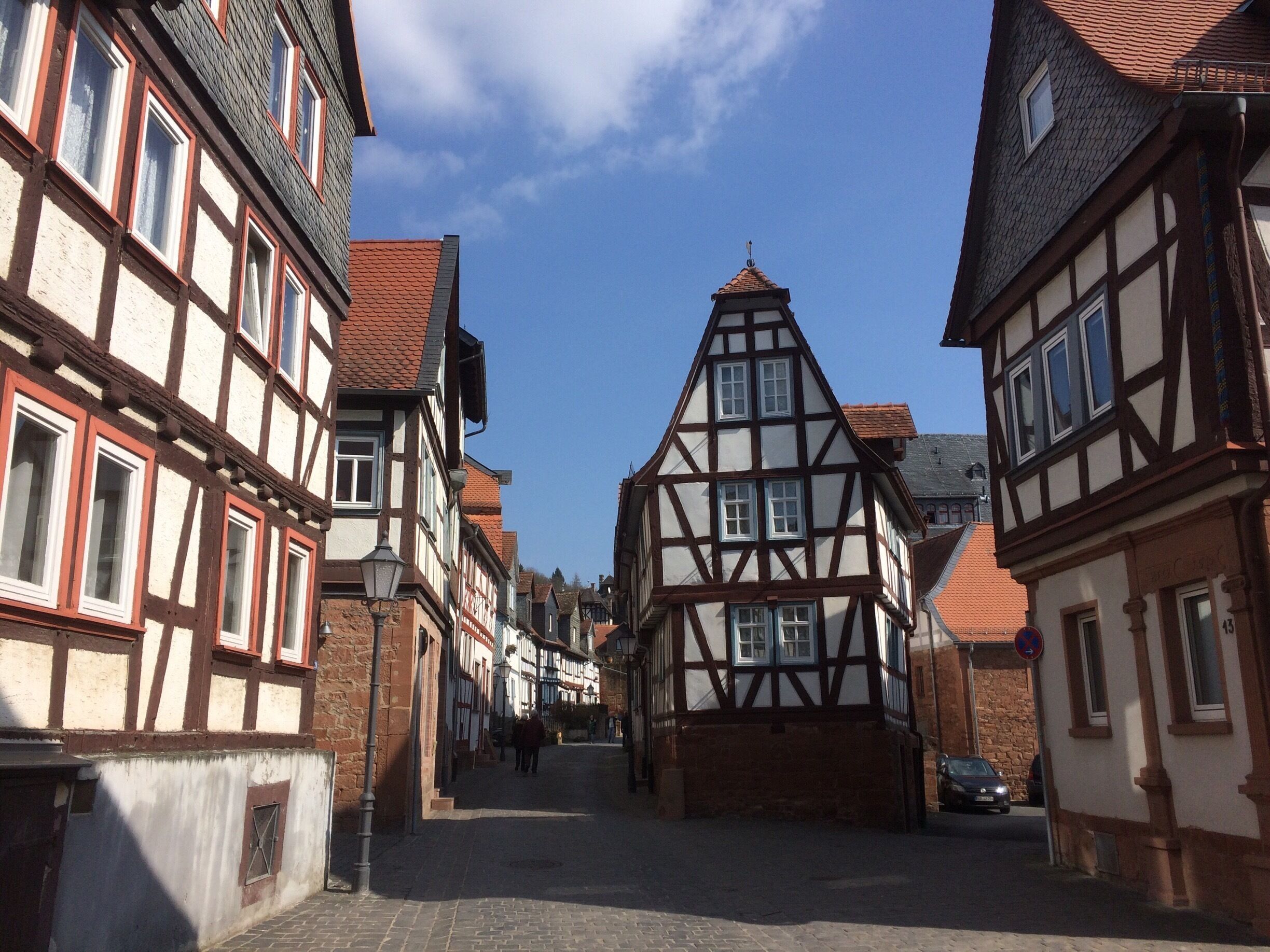 A narrow cobblestone street lined with traditional half-timbered houses.