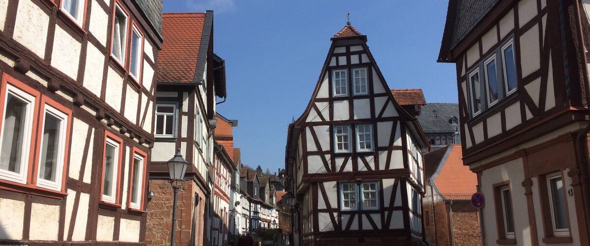 A narrow cobblestone street lined with traditional half-timbered houses.