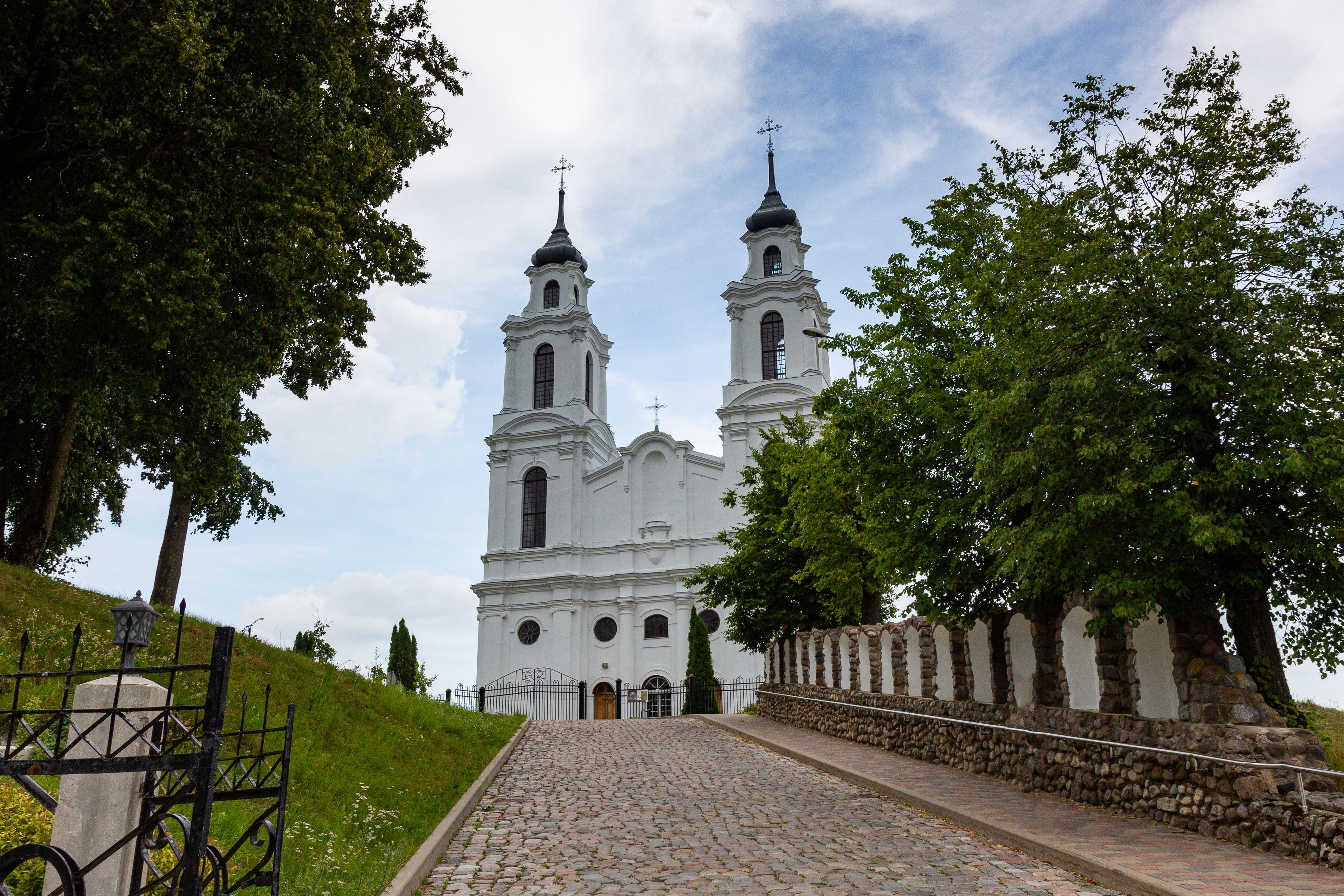 A white church with two towers and a stone wall.