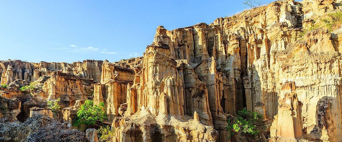 A rugged canyon with towering rock formations and sparse vegetation.